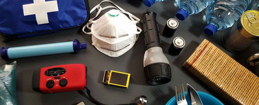 Billede af nødforsyninger til en prepper listee, herunder vand, radio, lommelygte, ansigtsmasker og førstehjælpsudstyr. Det perfekte til din prepper